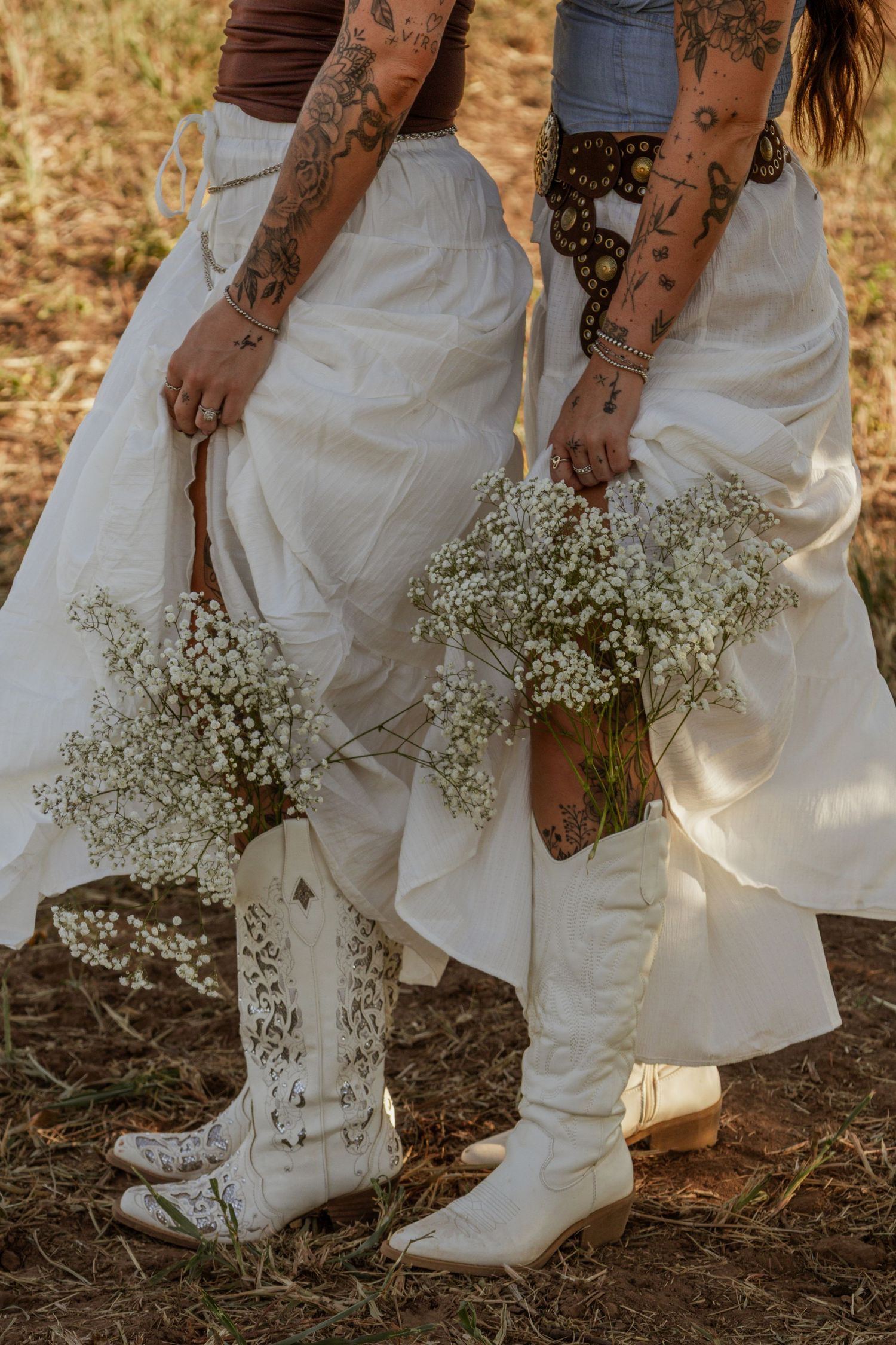 Close-up detail of a woman in a flowing white dress holding flowers during an outdoor creative portrait session.
