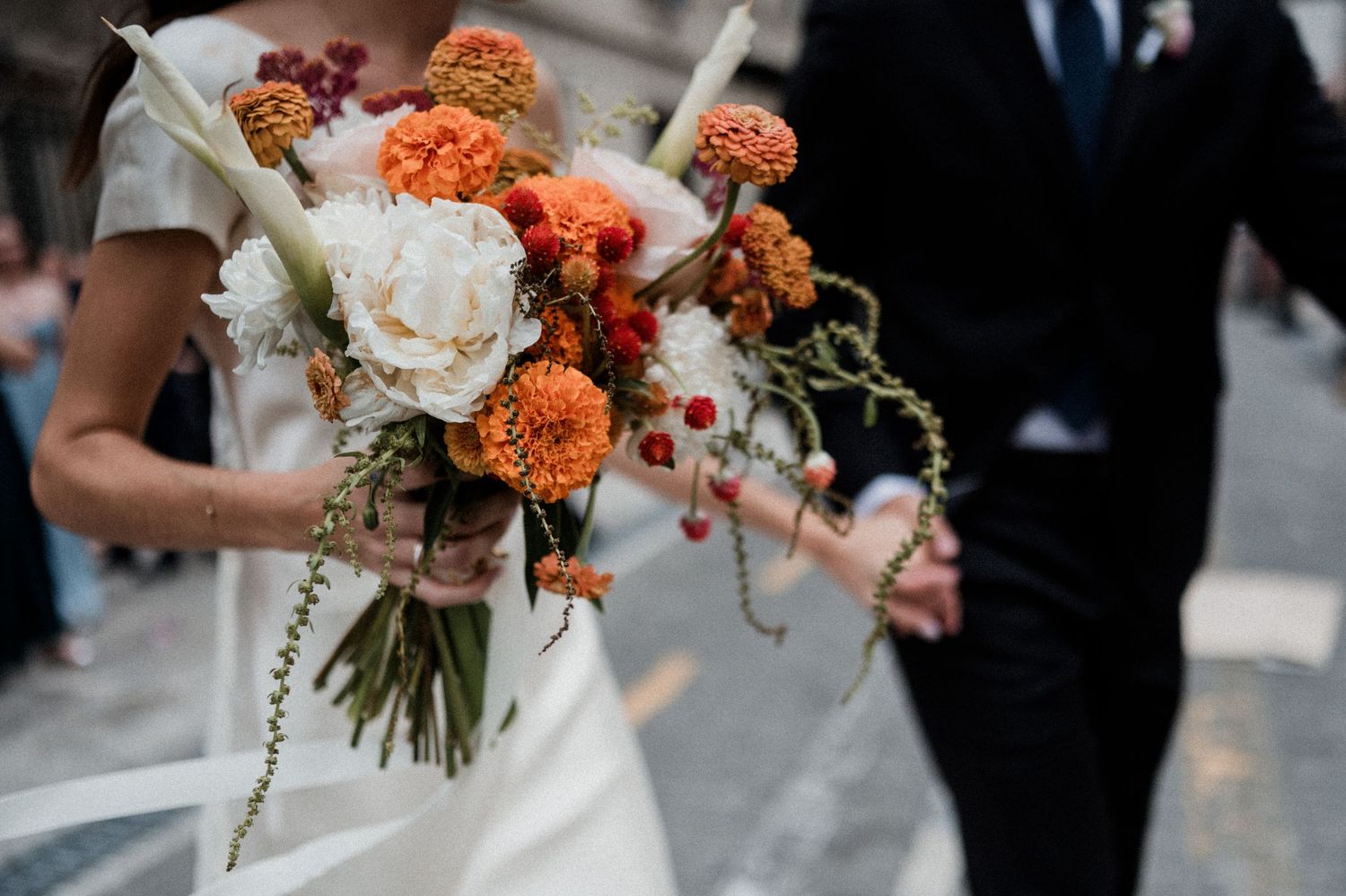Wedding couple sharing a joyful moment surrounded by smiling guests during an outdoor ceremony.