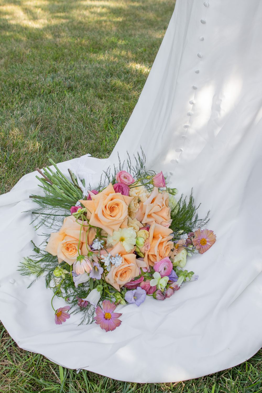 Wedding photographer in Strongsville places bouquet on bridal dress.