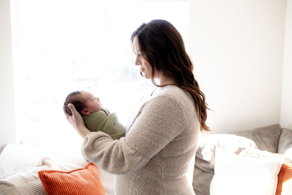 Mom holding baby during a newborn lifestyle session in Oak Ridge, TN with Nina Thomas Photography.