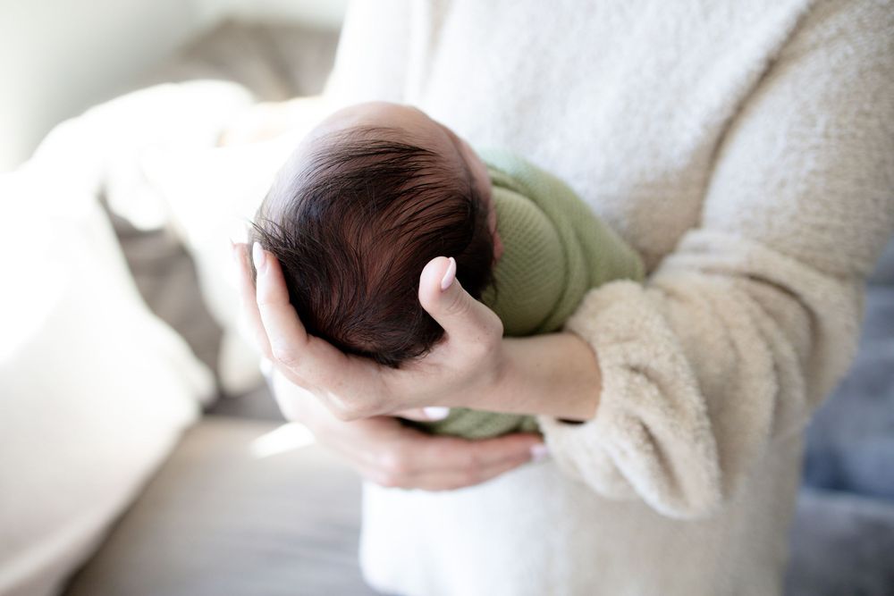 Mom holding baby during a newborn lifestyle session in Oak Ridge, TN with Nina Thomas Photography.