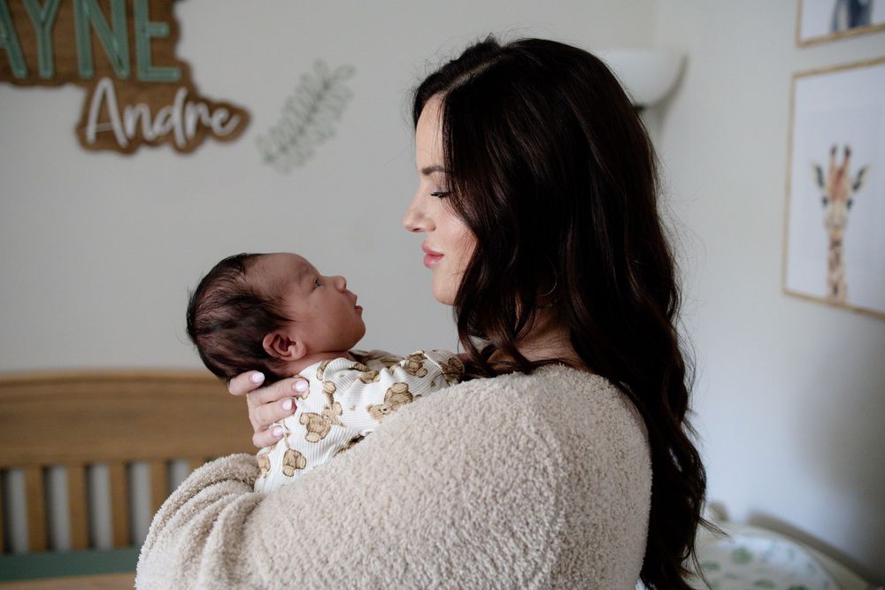 Mother with long dark hair gently cradling newborn during a newborn lifestyle session in Oak Ridge, TN with Nina Thomas Photography.