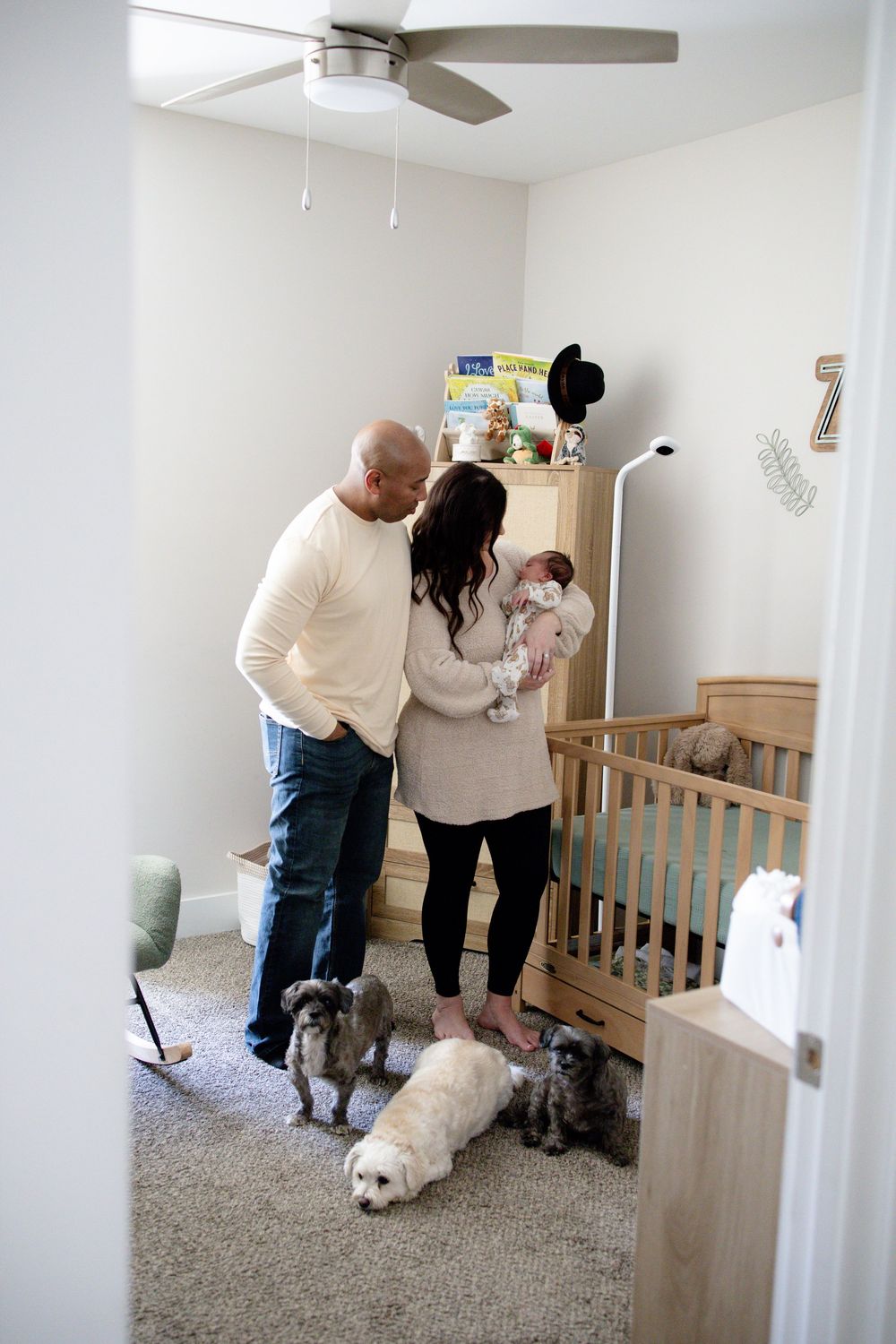 Parents hold a newborn baby in a cozy nursery during a newborn lifestyle session in Oak Ridge, TN with Nina Thomas Photography.