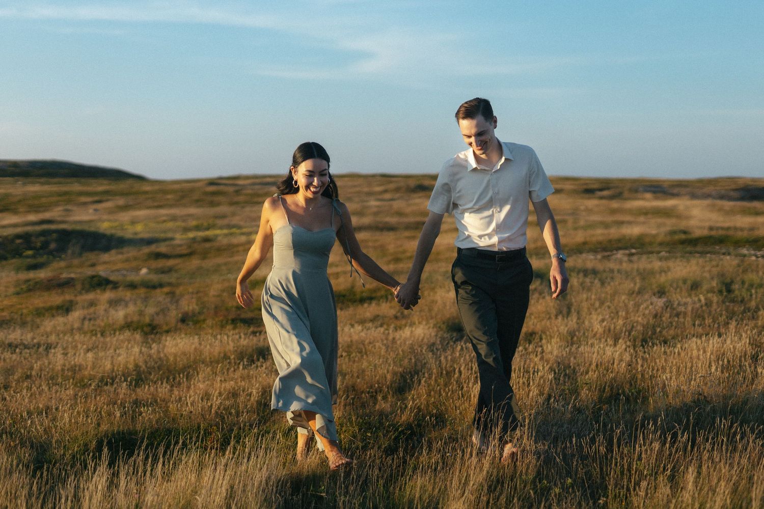 barefoot bride and groom laugh and walk through tall grass on Vancouver Island