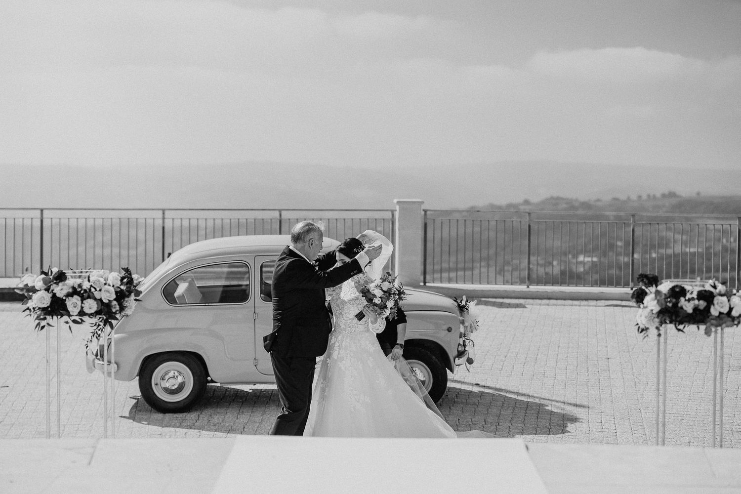 La sposa arriva davanti alla chiesa accompagnata da un uomo, in bianco e nero.