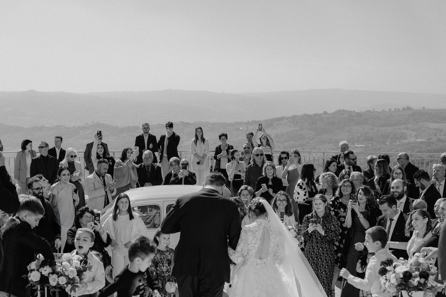 Gli sposi scendono tra gli invitati dopo la cerimonia, in bianco e nero.