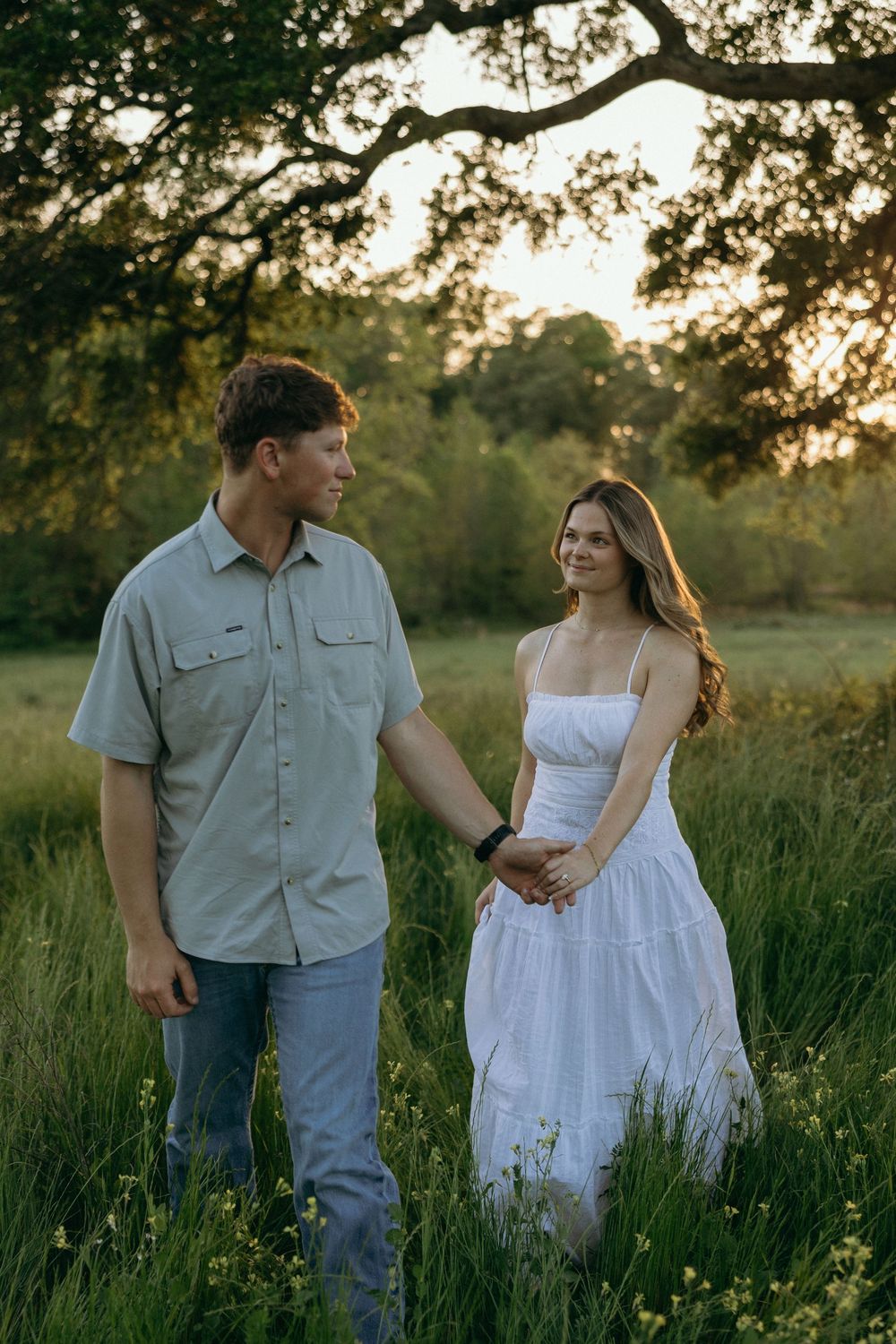 A couple is walking and holding hands while soft smiling at one another during their Atlanta engagement session.