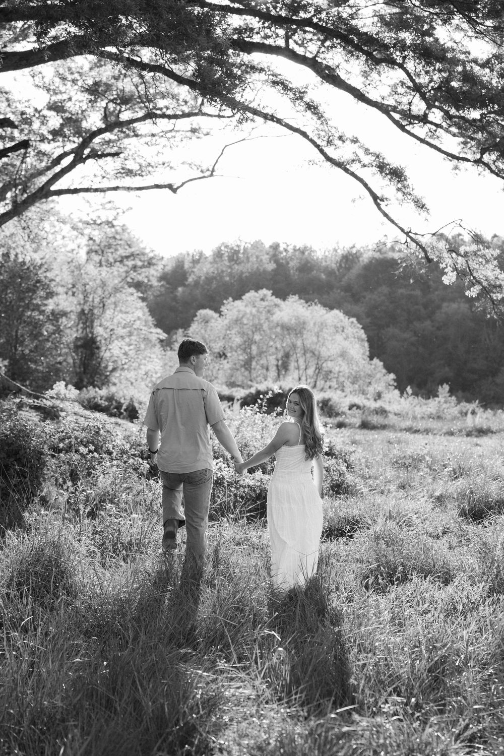 Black and white photo of a couple holding hands walking with Atlanta engagement photographer.