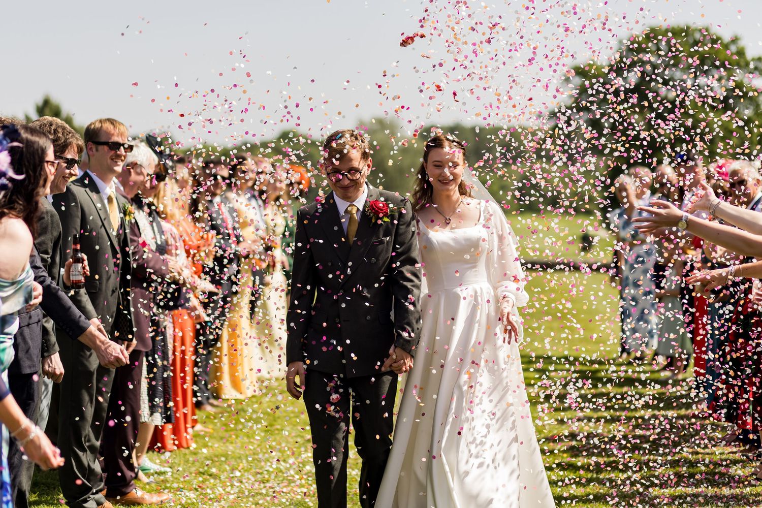 Wedding dress train flows dramatically against an ivy-covered brick wall background.