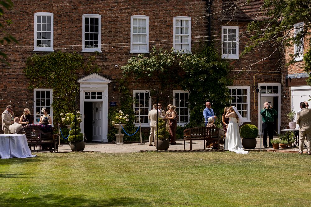 Elegant outdoor wedding reception on a sunny lawn in front of a classic red brick Georgian country house.
