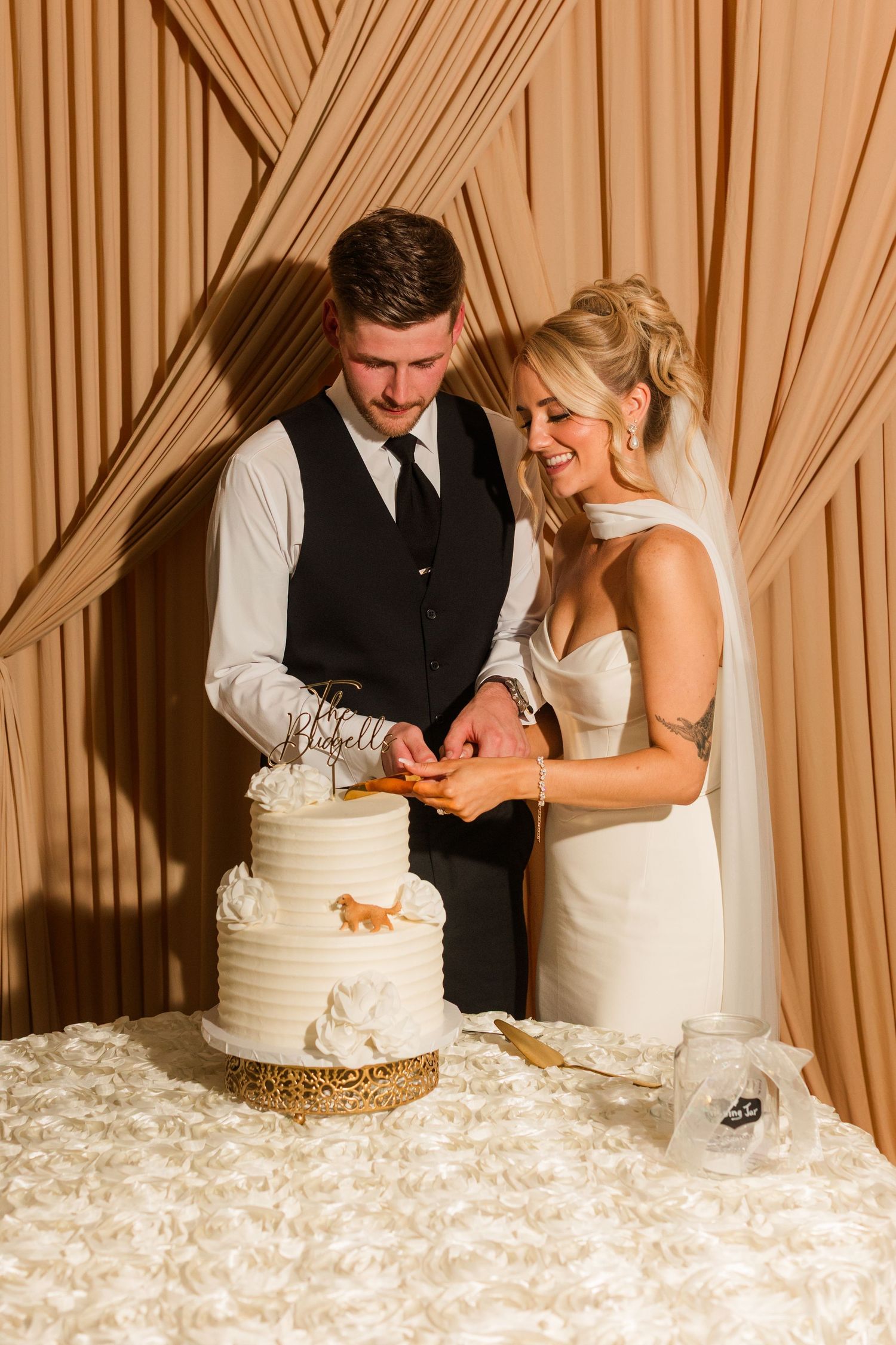 Bride and groom cutting their white three-tier wedding cake together at their reception.