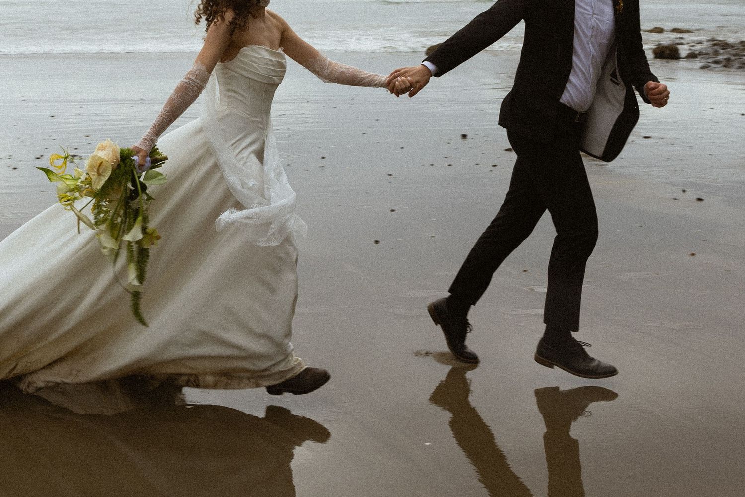 Black and white photo of two hands raised together, showing wedding rings, with sunlight in the background.