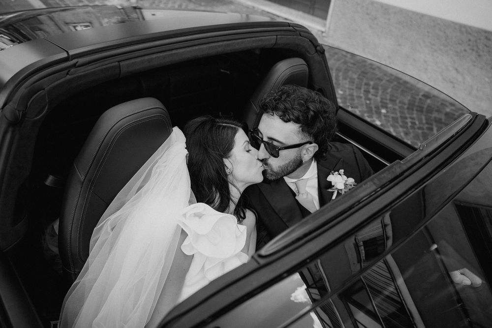 Un bacio di Lorenzo e Laura dentro l’automobile, ripreso dall’alto in bianco e nero.