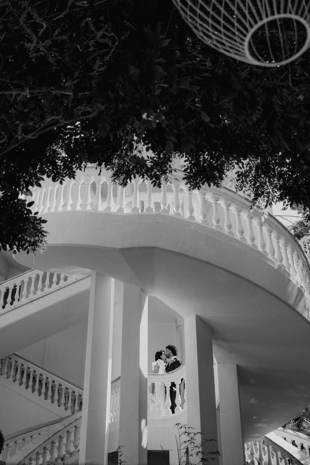 Gli sposi tra le scale e le linee bianche dell’architettura, incorniciati dal verde in bianco e nero.