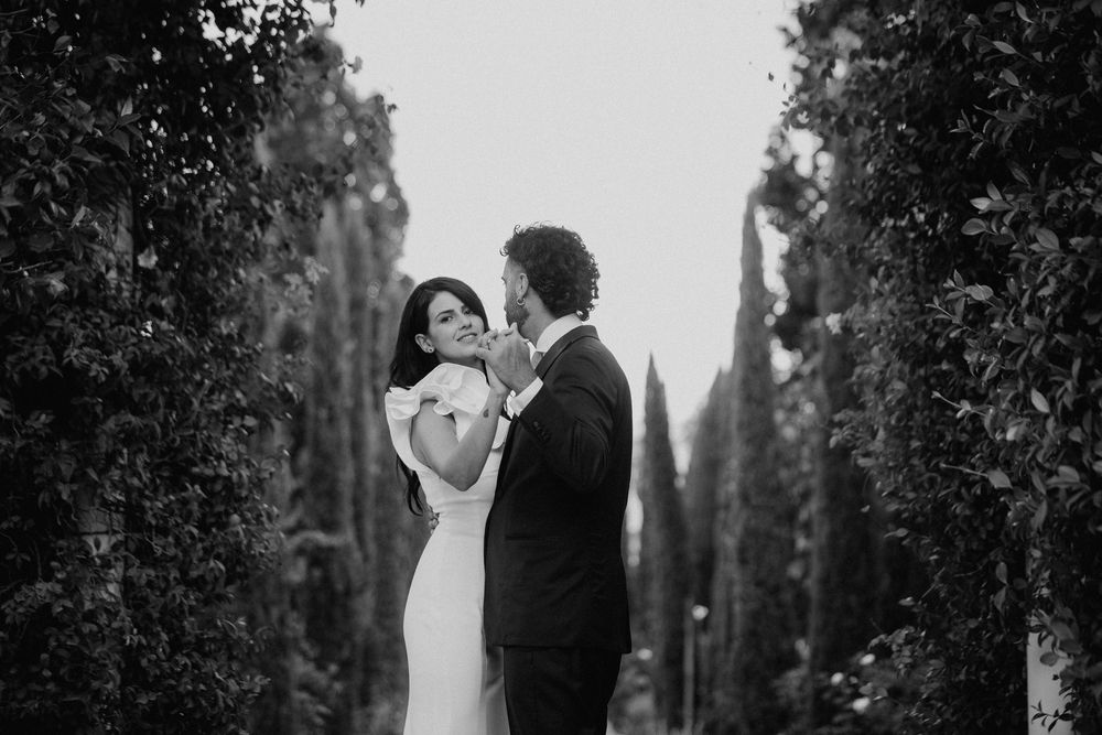 Lorenzo e Laura si avvicinano tra gli alberi, in una fotografia in bianco e nero.