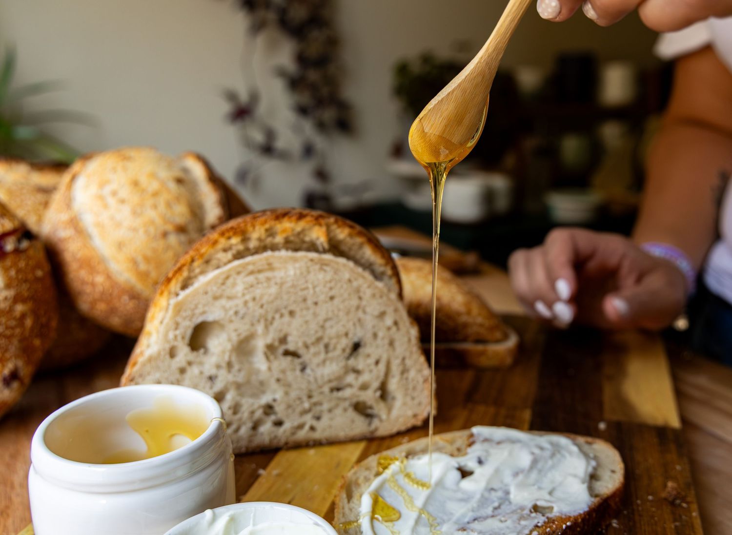 Honey drizzled over fresh sourdough bread on a wooden board with creamy butter spread nearby.