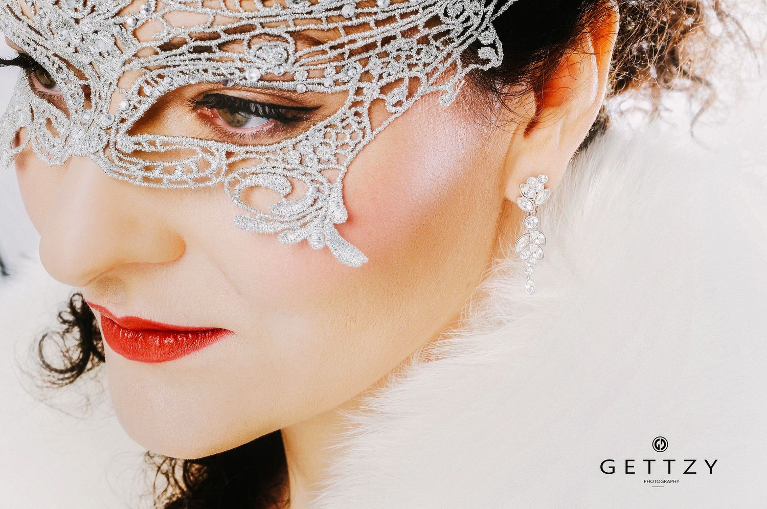 Artistic close-up with silver lace mask and bold red lipstick.
