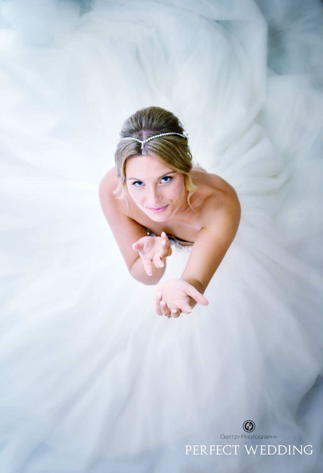 Overhead view of a person in a flowing white wedding gown against a light background.