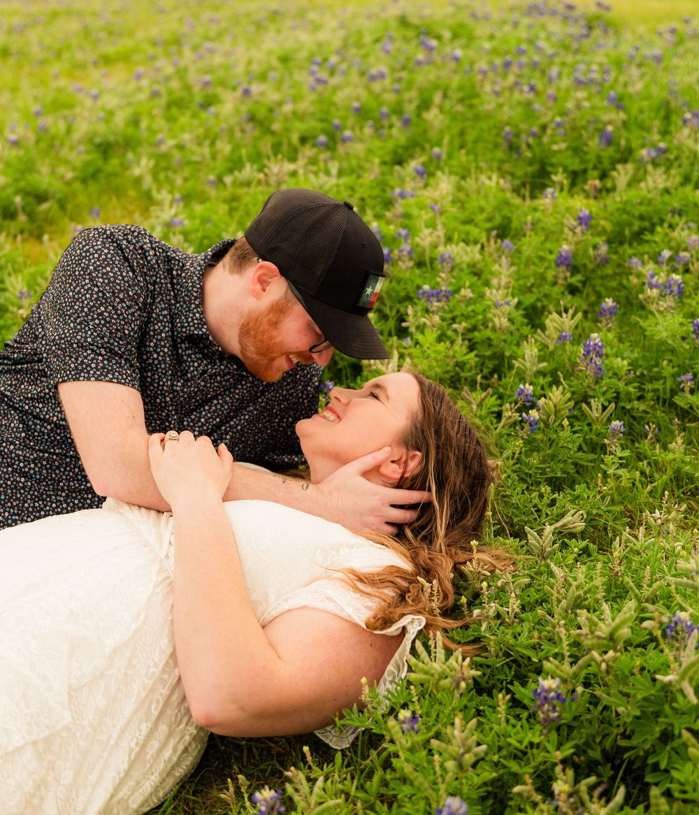 Couple sharing a romantic moment lying in a field of purple wildflowers.