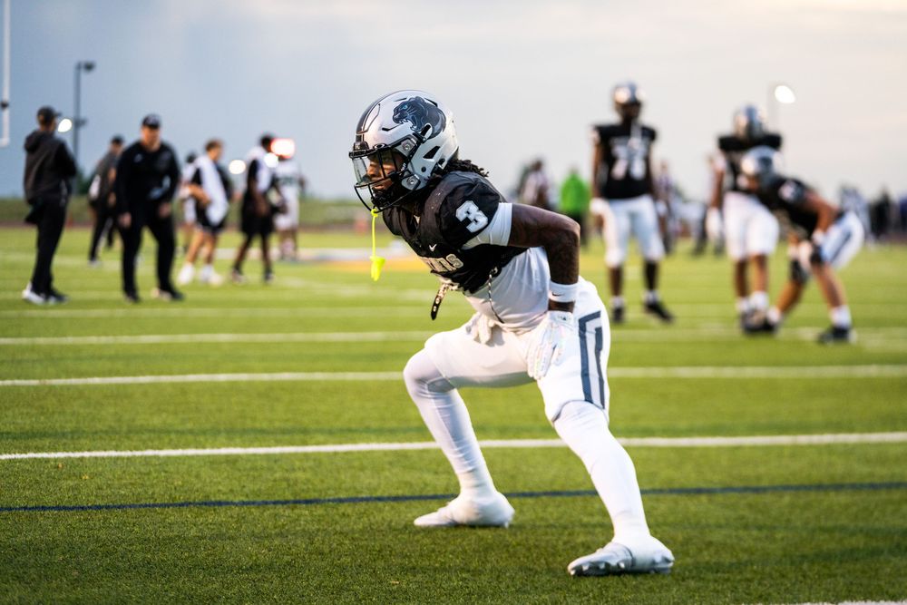 Football player in black and white uniform warming up.