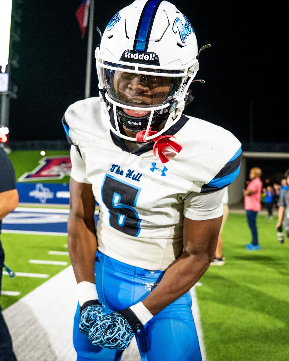 Football player in blue and white uniform number 6 on sideline during a night game.