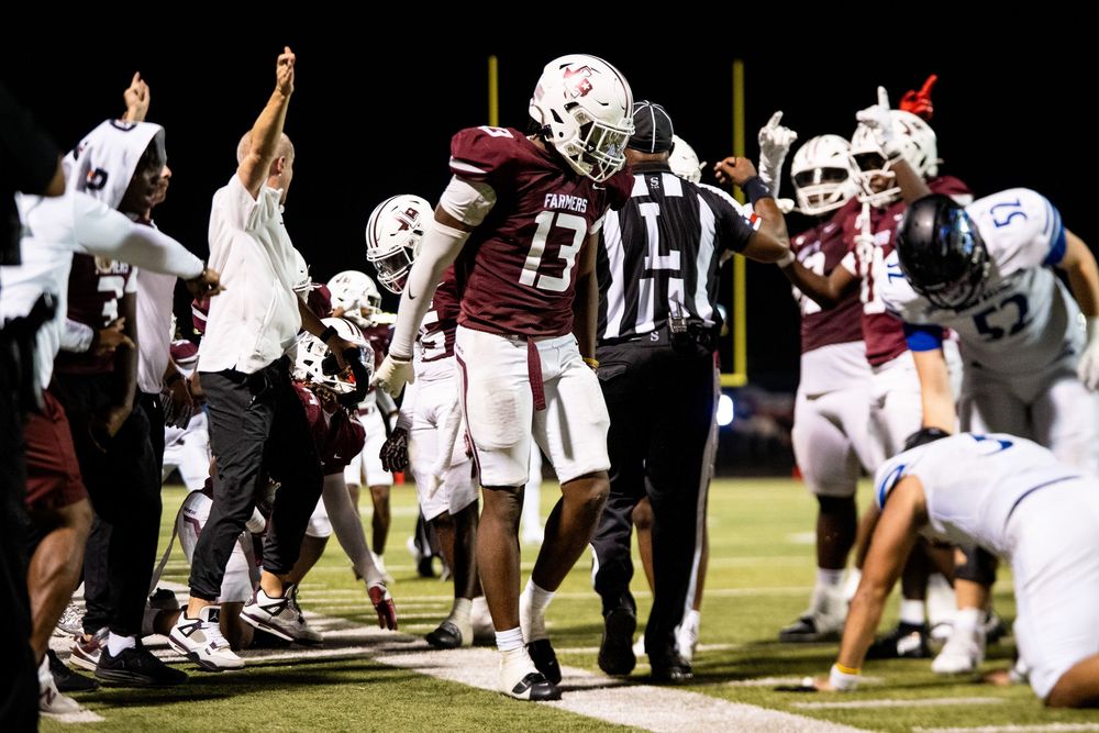 Football player #13 in maroon uniform celebrates on the field during a night game.