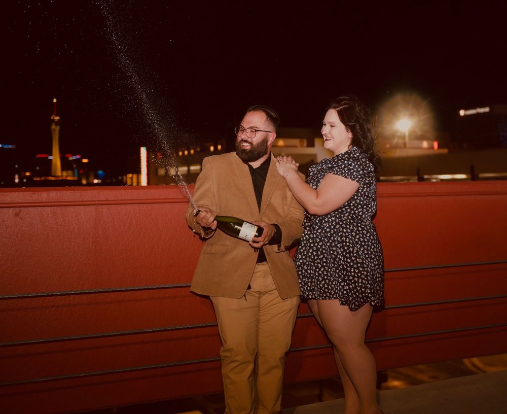 Couple celebrating with champagne on a rooftop at night in Las Vegas.