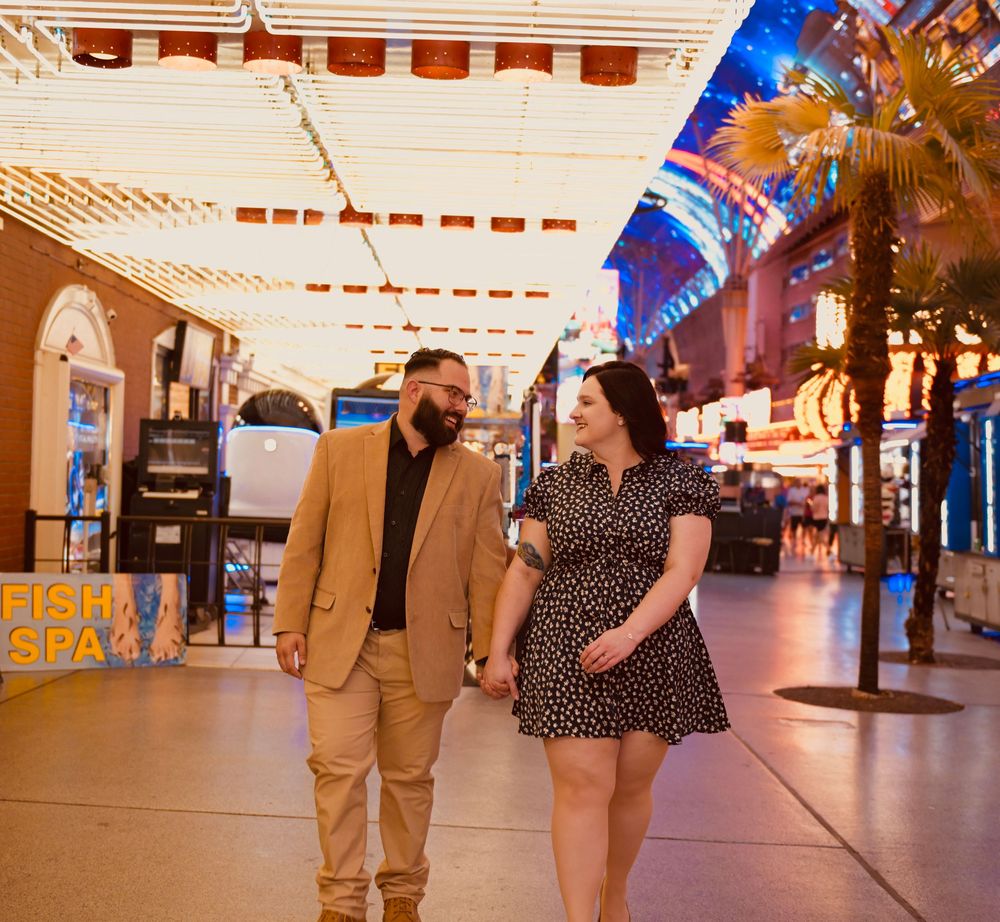 Couple holding hands and walking together under bright lights at Fremont Street Experience in Las Vegas.