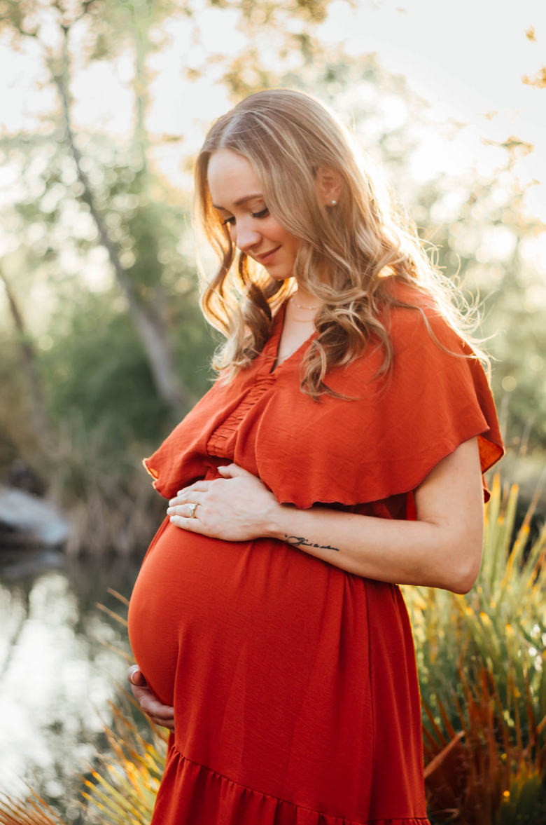 Pregnant woman gazes down at her belly lovingly at Agua Caliente Park maternity shoot.