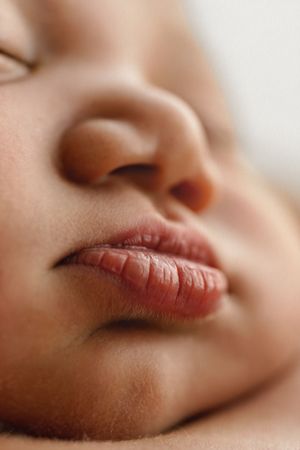 Close-up of a sleeping baby's face showing delicate lips and nose in soft focus.