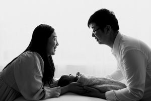 Black and white photo of parents smiling at their newborn baby during an intimate family portrait session.