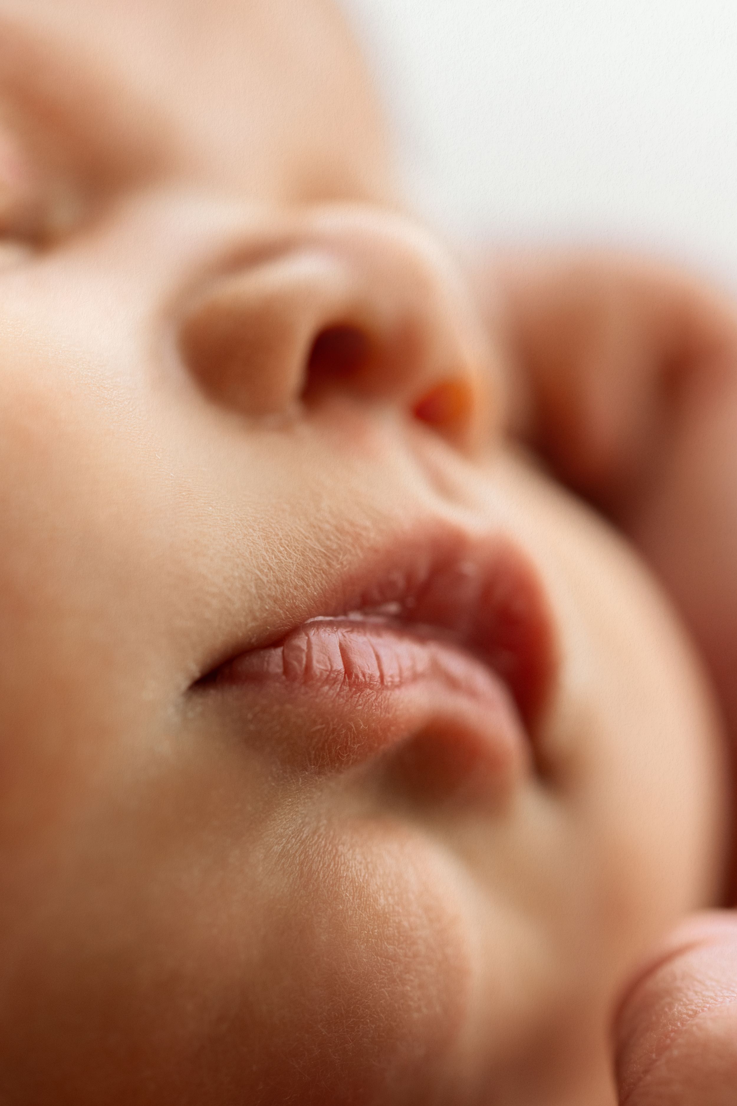 Close-up of a peaceful sleeping newborn baby's face showing delicate lips, nose, and soft skin.