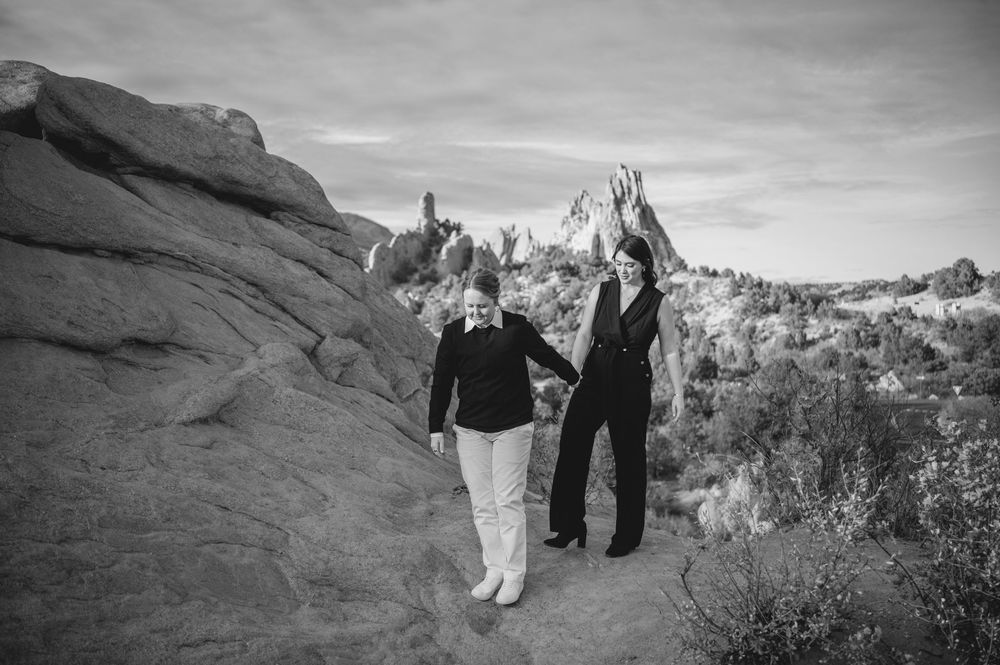 Black and white photo of two women holding hands on a rocky trail at Garden of the Gods, Colorado.