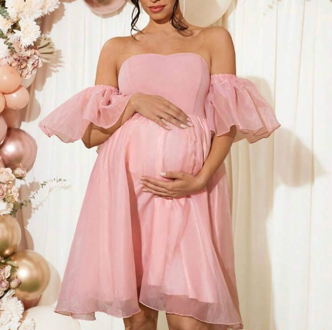 Pink off-shoulder maternity dress with puff sleeves and flowing skirt, perfect for baby shower photos.