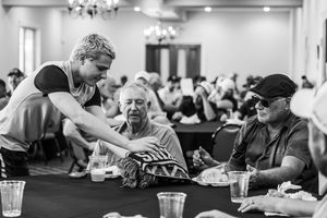 Young volunteer serves elderly guests at a banquet hall dinner event in black and white photography.
