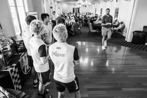 Black and white photo of youth soccer players in Xtreme jerseys listening to a coach in a banquet hall.