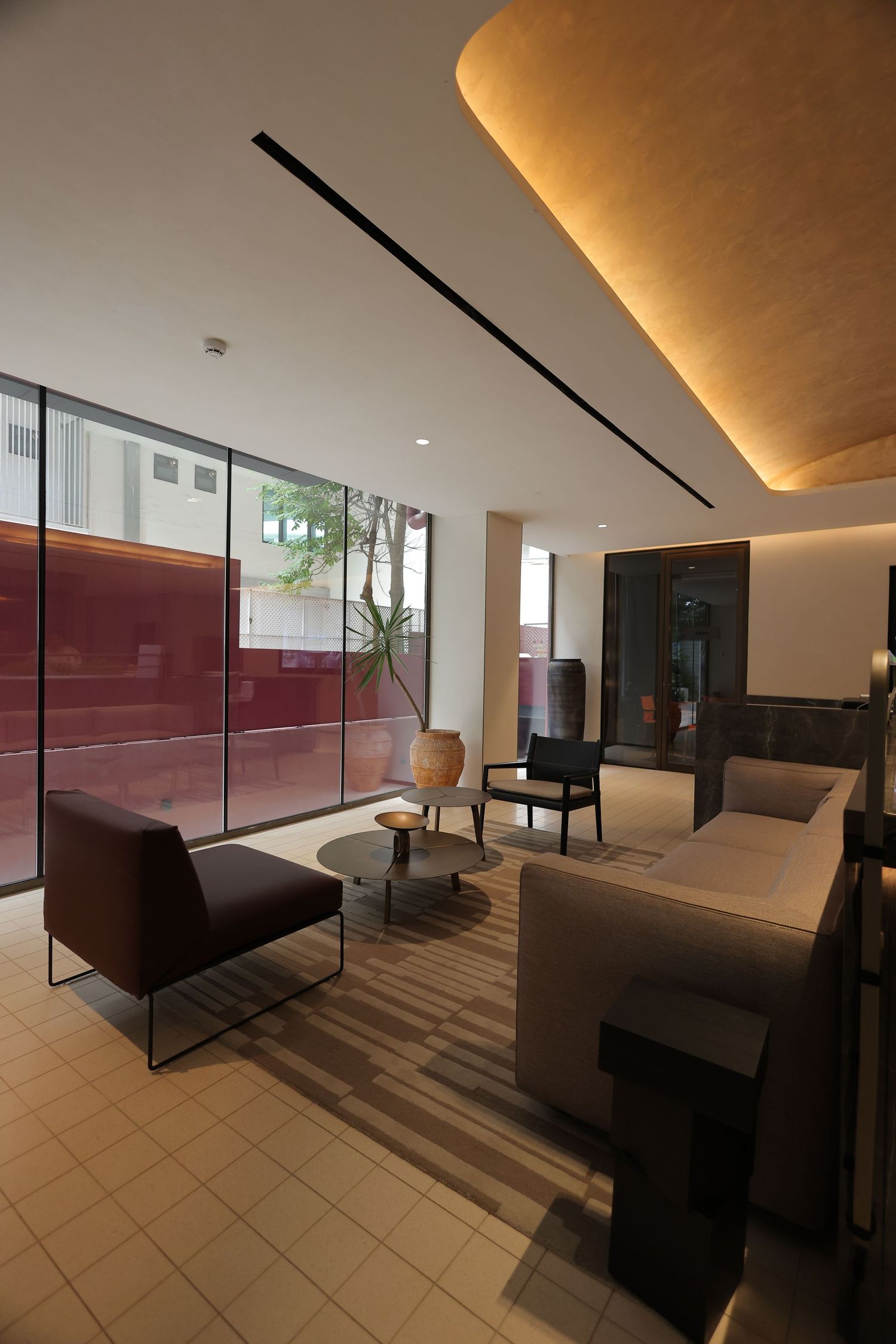 Modern hotel lobby lounge with warm ambient lighting, large windows, and contemporary furniture on striped carpet.