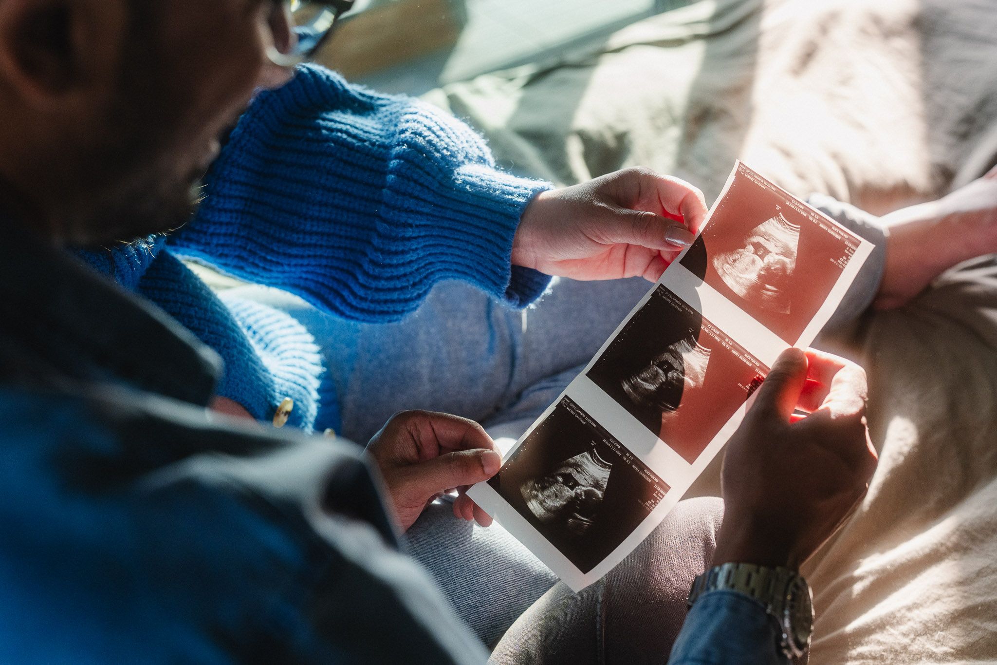 Expecting parents looking at ultrasound photos together during their Pasadena maternity session
