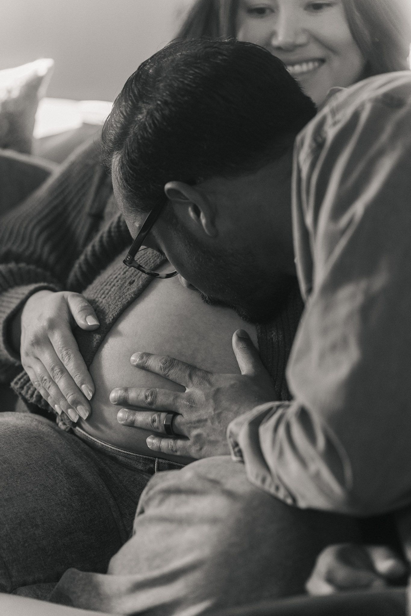 Rohan gently kissing Amanda’s baby bump during an intimate maternity session at home