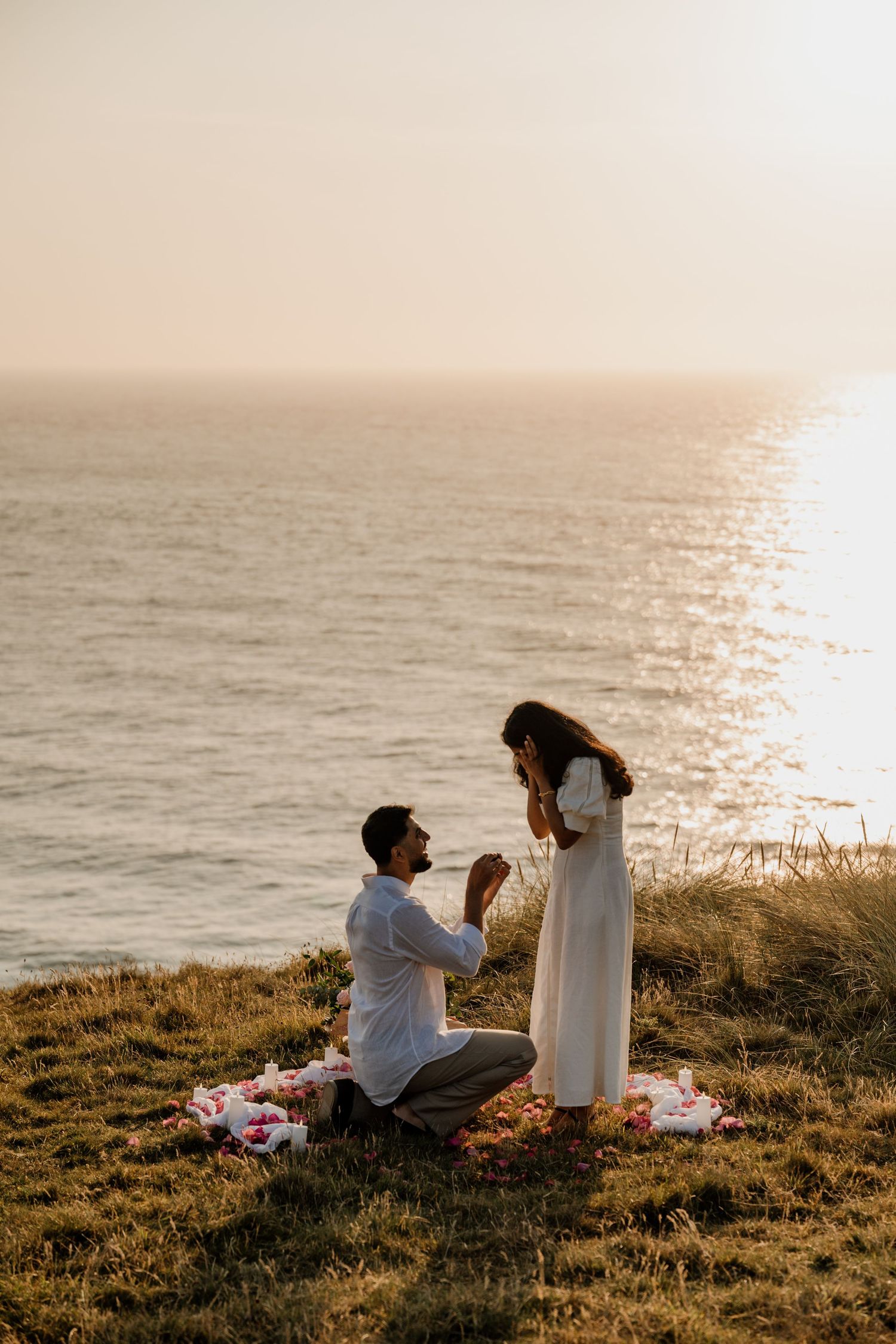 Man proposes to woman on grassy cliff on the cliffs at Holywell Bay,