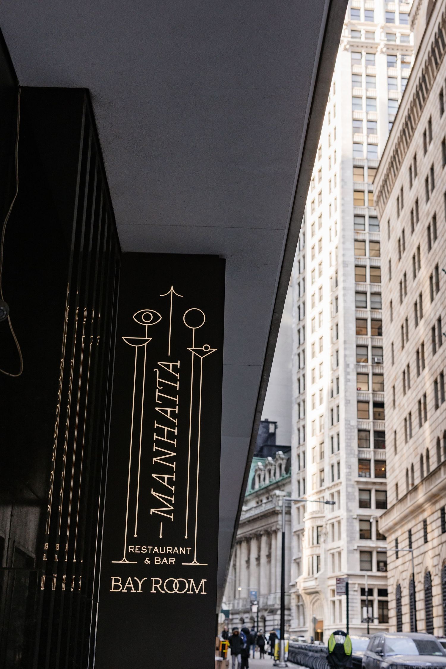 Manhatia Restaurant & Bar Bay Room sign on a dark exterior wall in New York City.