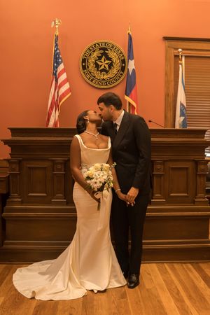 Bride and groom share a kiss at Fort Bend County courthouse wedding ceremony in Texas, bride holding white bouquet.