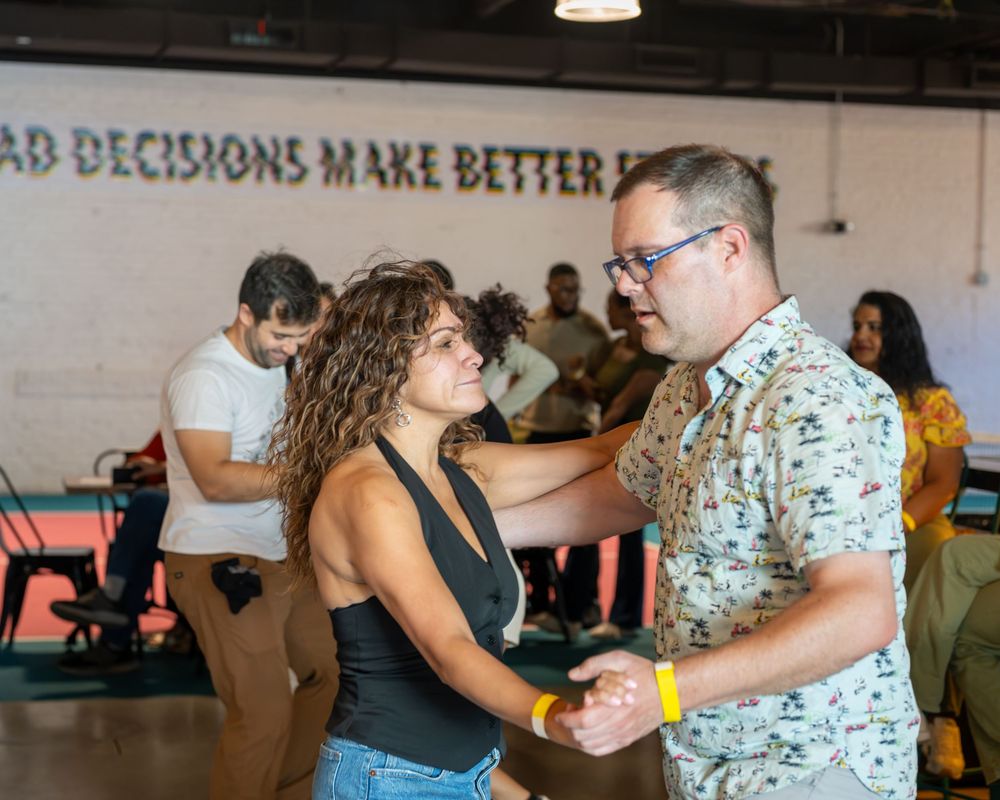Couple dancing together at a lively indoor social event with people in the background.