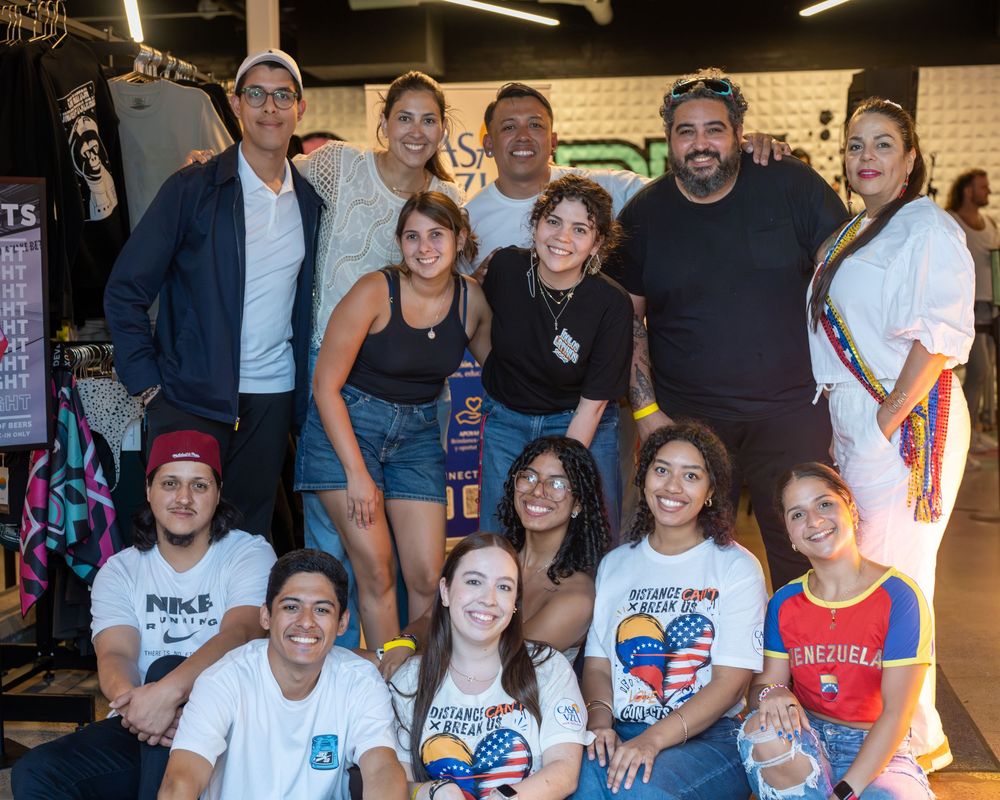 Group of diverse friends posing together at an indoor event, wearing casual clothes and smiling for a group photo.