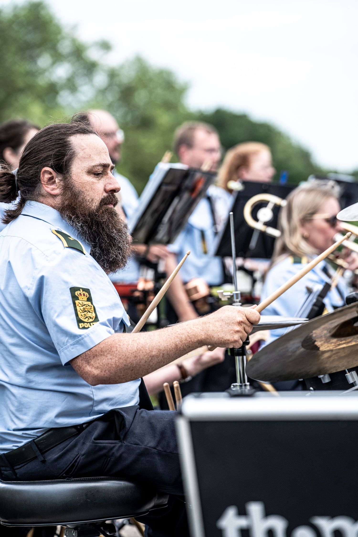 People clinking glasses with an orange cocktail on ice at an outdoor event, wearing festival wristbands.