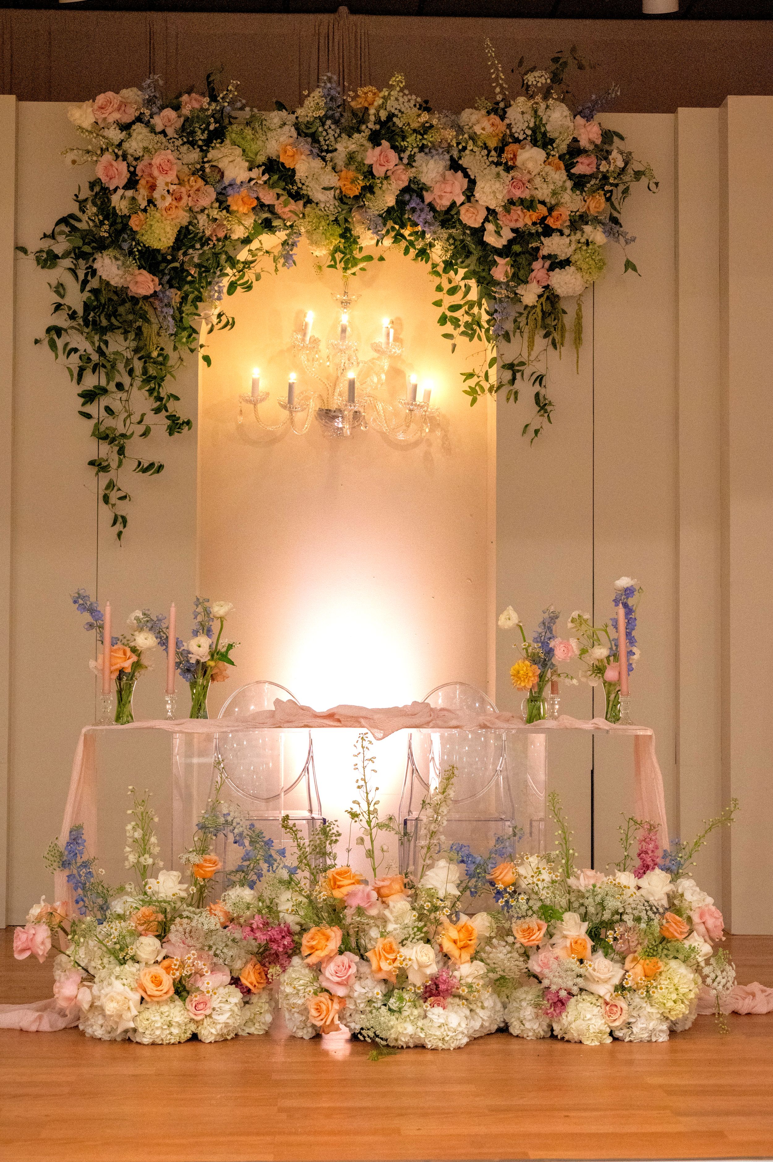 Elegant wedding reception table with floral chandelier arrangement and soft candlelight.