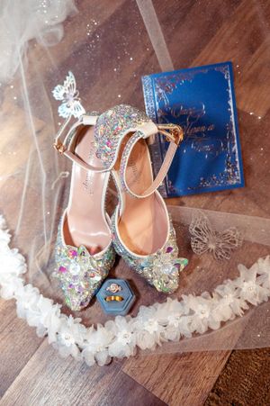 Glittering bridal shoes with butterfly details displayed with blue stationery and decorative elements.