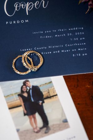 Wedding invitation for Cooper Purdom on navy blue background with gold rings and couple photo for March 20 2026 ceremony.
