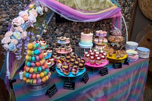 Colorful dessert table with macarons, cupcakes, and tiered cakes at a festive celebration.
