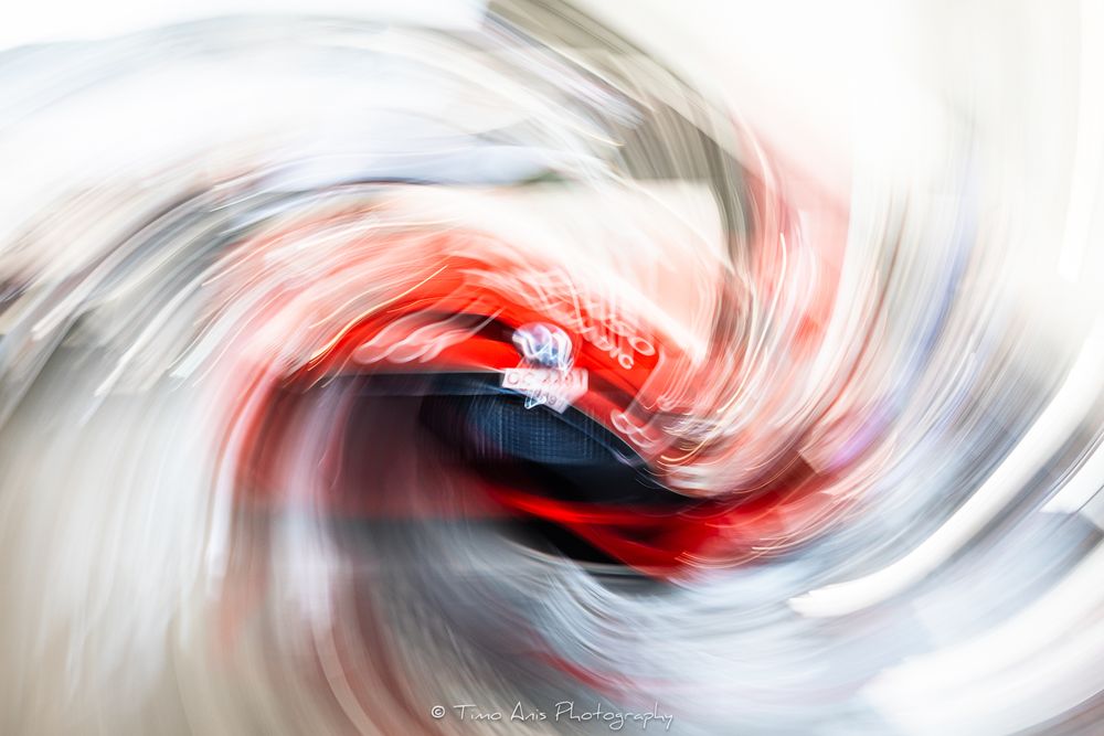 Abstract swirling motion blur of red and white colors creating a dynamic spiral effect in sports photography.
